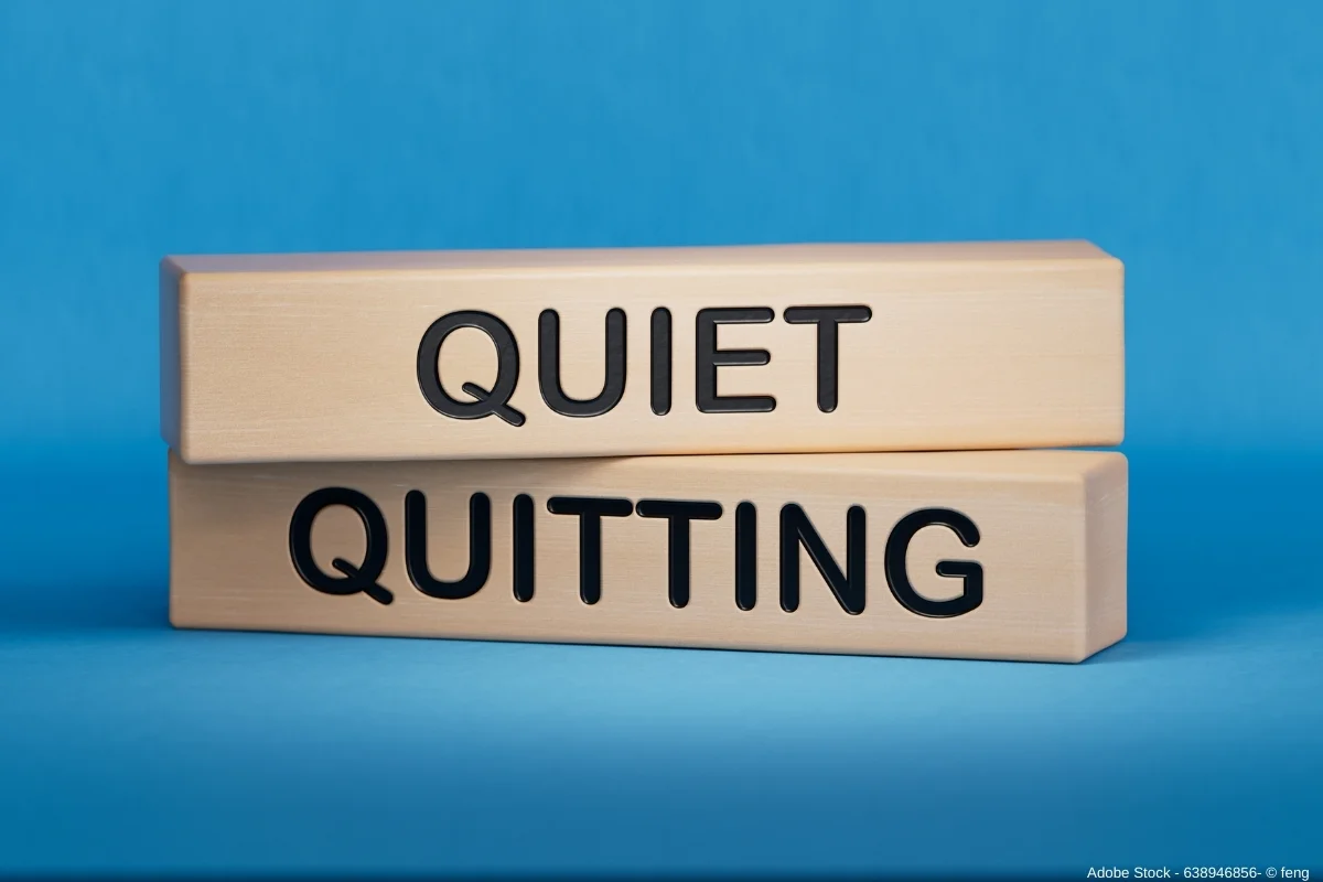 Holzblöcke mit den Worten „Quiet“ und „Quitting“ auf blauem Hintergrund veranschaulichen das Thema Quiet Quitting im Arbeitskontext.